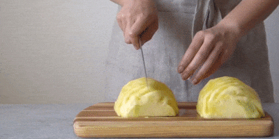 Как порезать ананас дольками: разрежьте фрукт вдоль пополам, затем каждую половинку разделите ещё на две длинные части.