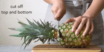 Как почистить ананас: положите фрукт горизонтально на разделочную доску, отрежьте верхушку и нижнюю часть