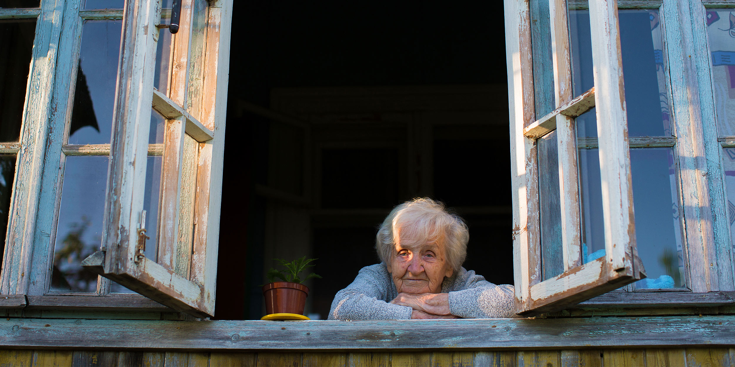 Жилье старика и старухи. Старушка выглядывает из окна. Окно в доме престарелых. Бабушка выглядывает из окошка. Стар дом для пенсионеров.