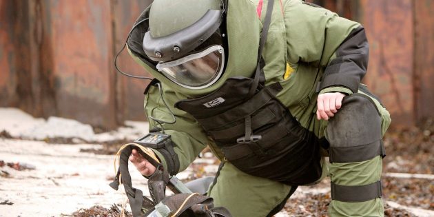 Сапёр в защитном костюме EOD обезвреживает противопехотную мину