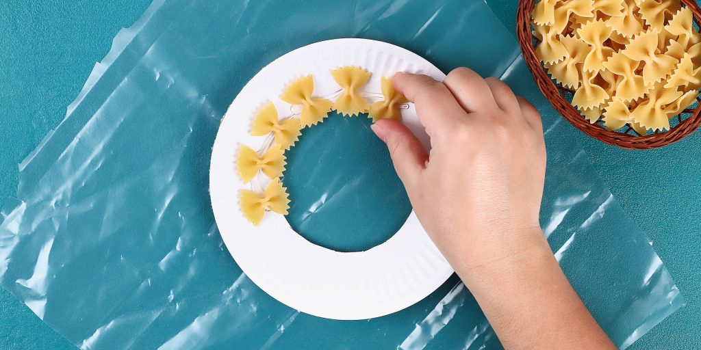 Венок из макарон: макароны смажьте клеем и по кругу друг за другом приклейте к основе