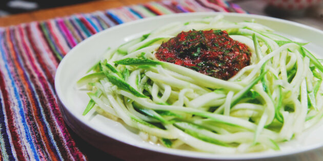Выложите спагетти из кабачков на плоскую тарелку и полейте томатным соусом