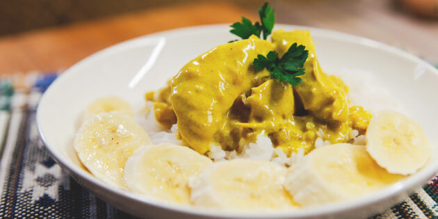 Serve chicken curry with rice and garnish with bananas.